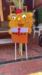 Hay figure with red cap, googly eyes.