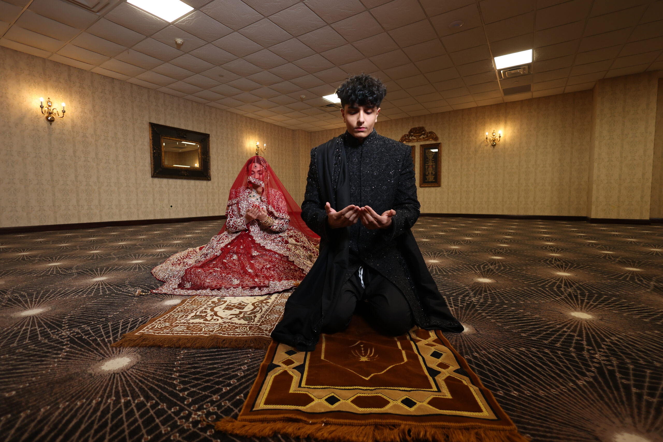 Bride and groom praying in ceremony hall.