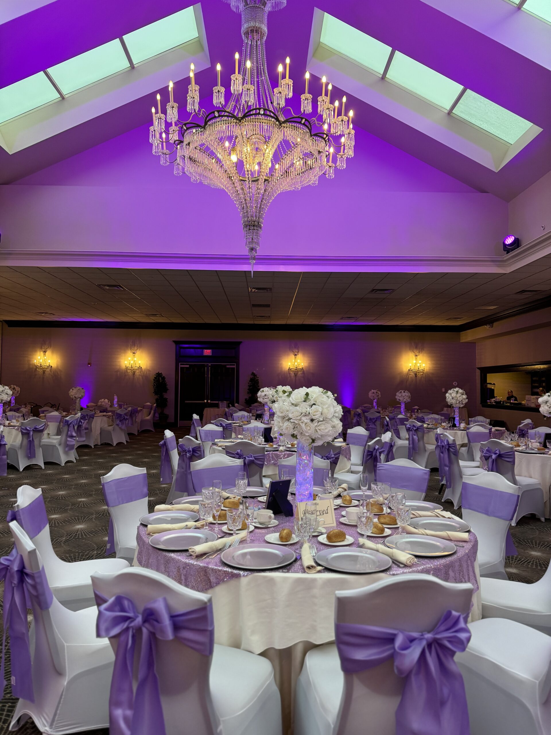 Elegant banquet hall with purple decor and chandelier.