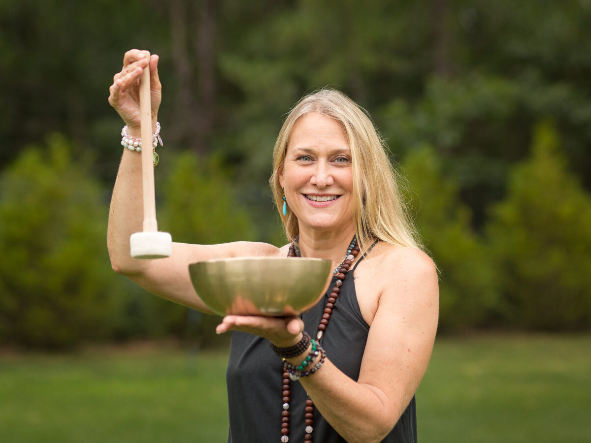 Smiling woman with singing bowl outdoors