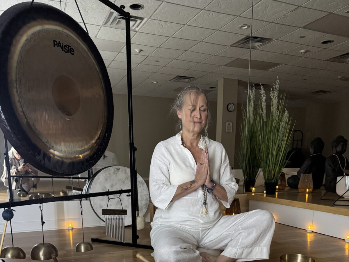 Woman meditating with sound bowls and candles.