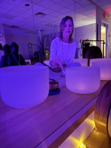 Woman with singing bowls, purple ambiance.