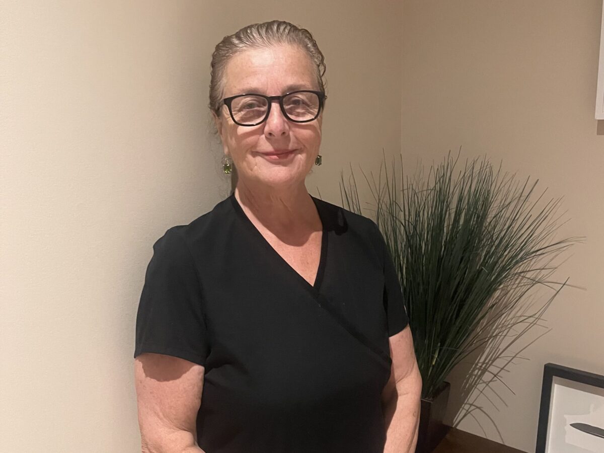 Senior woman with glasses smiling indoors.