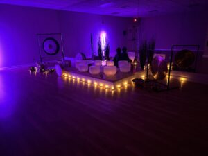 Purple-lit meditation room with gongs and candles.