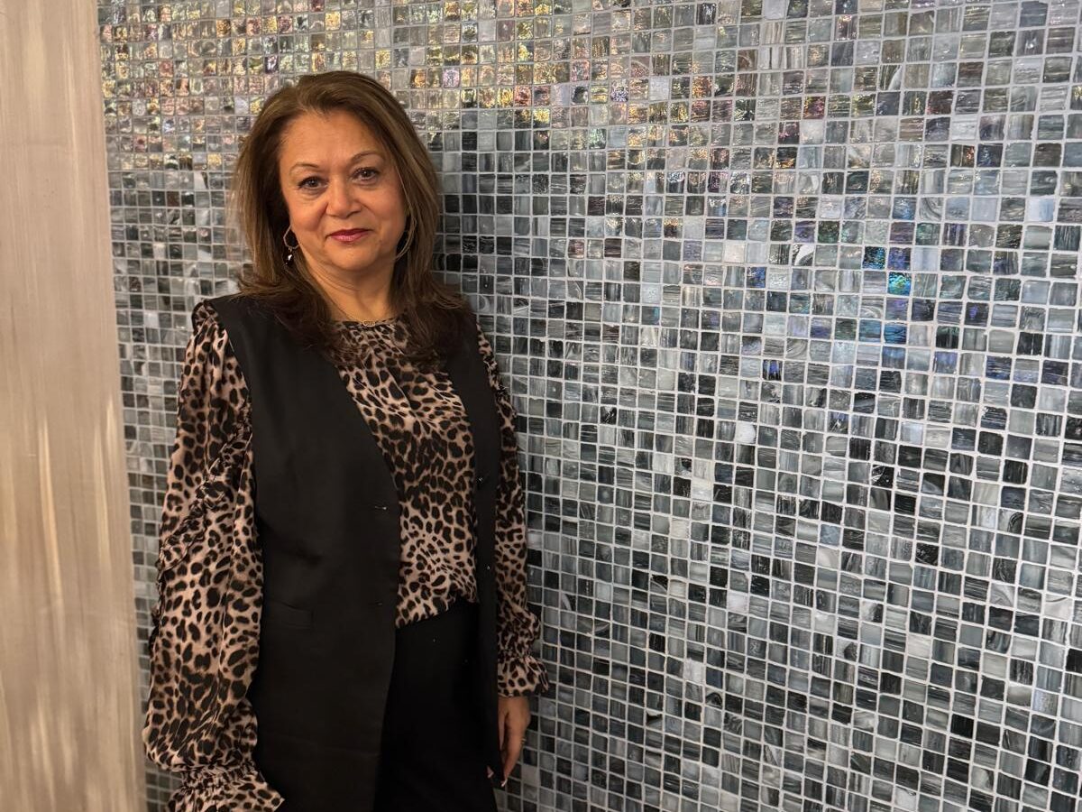 Woman in leopard print near mosaic wall.