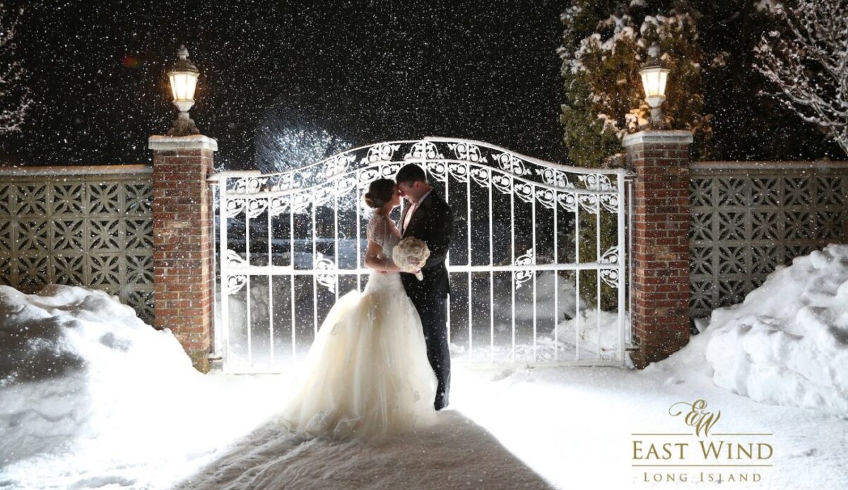 Snowy wedding kiss by ornate gate